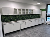 Stół przyścienny z szafkami wiszącymi pełnymi i przeszklonymi do szkolnej pracowni chemicznej.